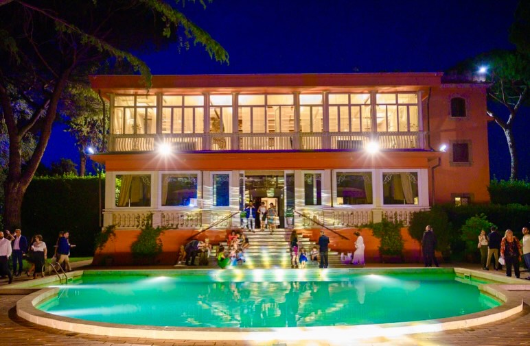 Villa Dafne Majestic e la piscina illuminate di notte durante un evento aziendale